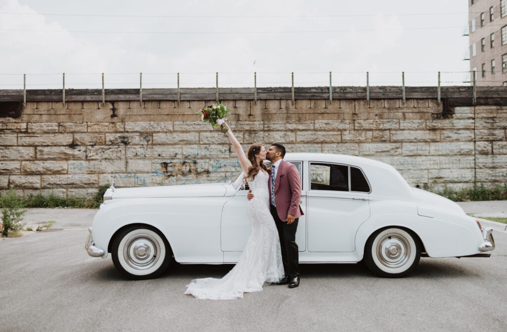 Couple celebrates and kisses in front of vintage car in Chicago